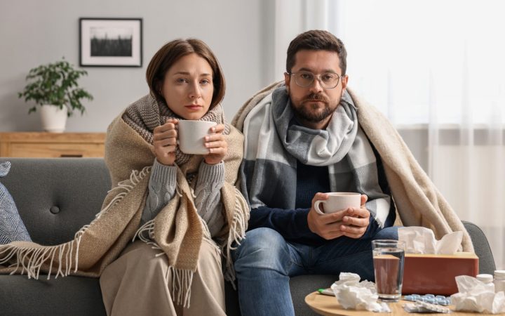 femeie și bărbat înfrigurați și răciți care beau ceai