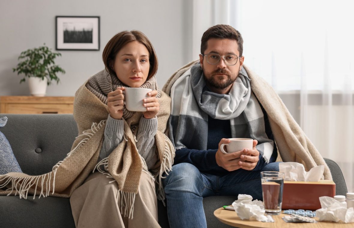 femeie și bărbat înfrigurați și răciți care beau ceai