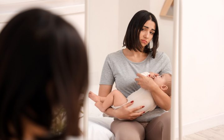 mamă în oglindă cu bebelușul în brațe tristă pentru că soțul este interesat de altă femeie