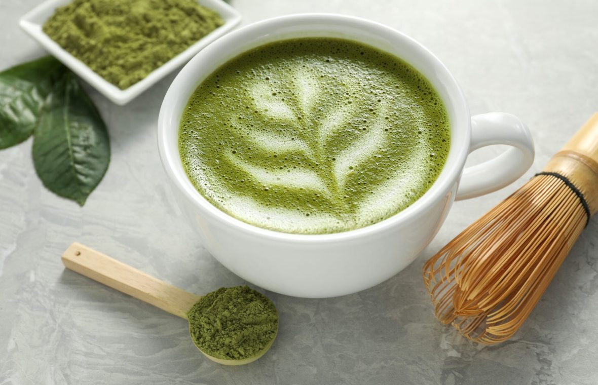matcha cu lapte langa un castron cu pudra și un tel tradițional din bambus