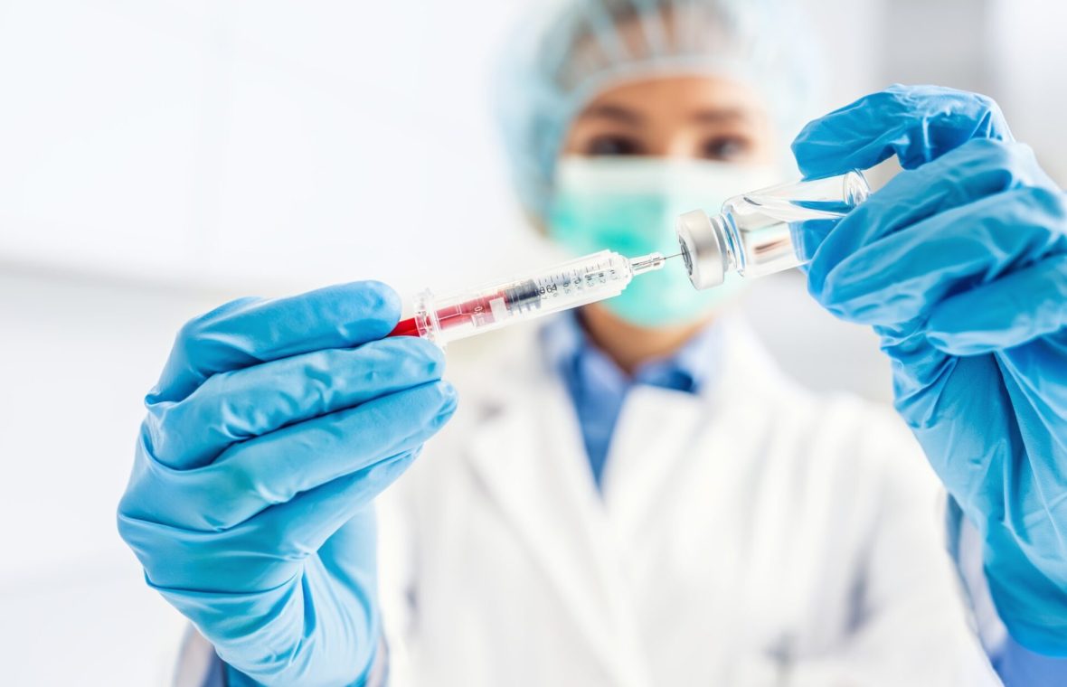 femeie om de știință extrage cu o seringă un vaccin pentru cancer