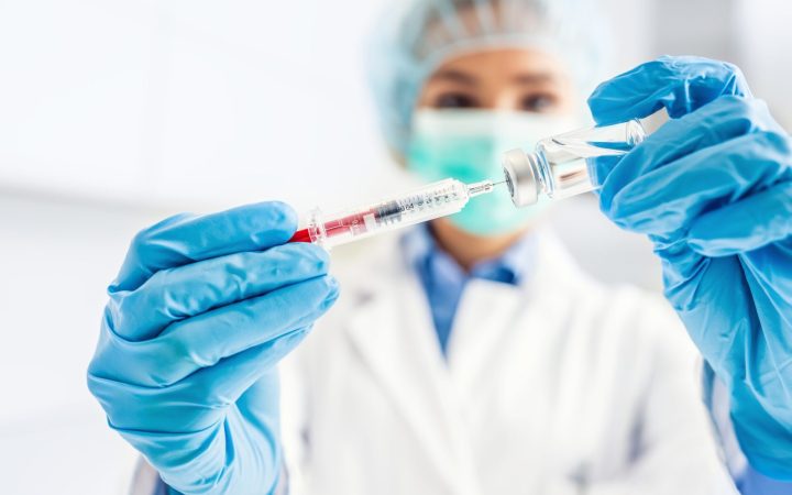 femeie om de știință extrage cu o seringă un vaccin pentru cancer