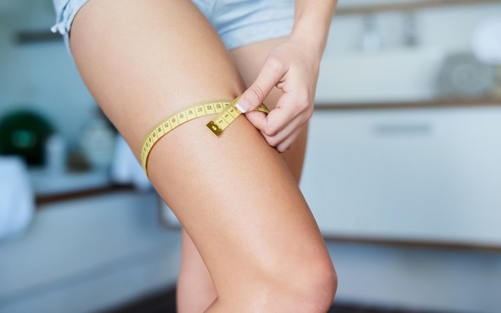 femeie care-și măsoară coapsa dreaptă cu centimetrul