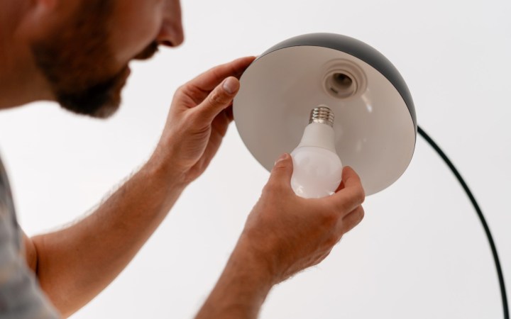 bărbat care schimbă becul la o lampă