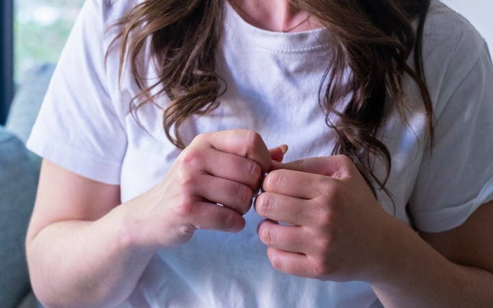 femeie tânără cu adhd care nu se poate relaxa, își frământă mâinile cu neliniște