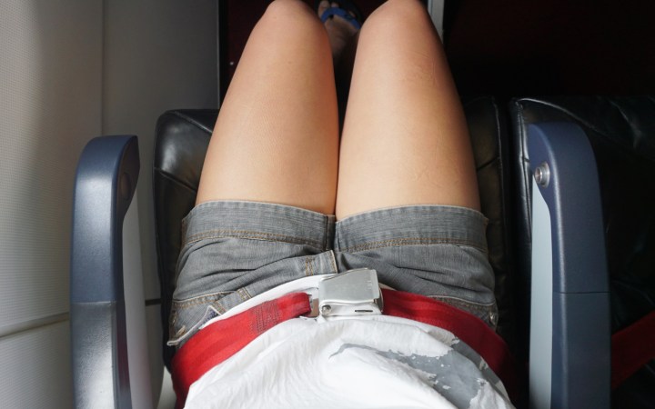 femeie cu pantaloni scurți în avion, cu centura pusă