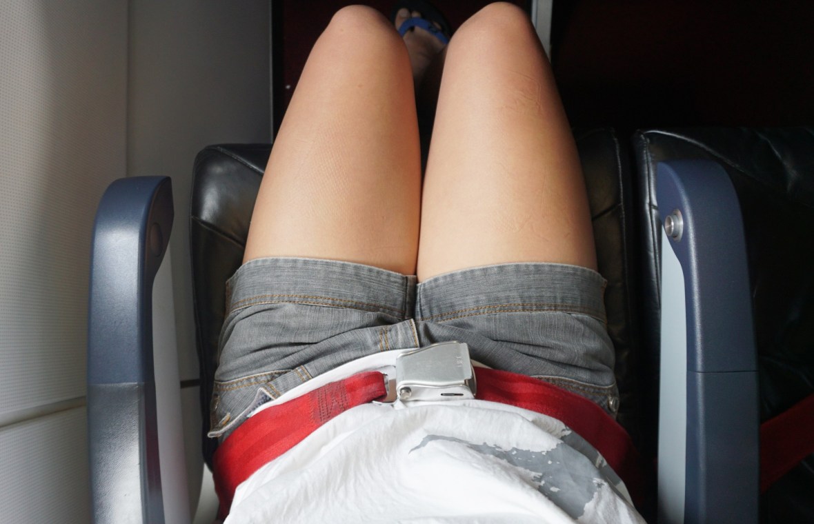 femeie cu pantaloni scurți în avion, cu centura pusă