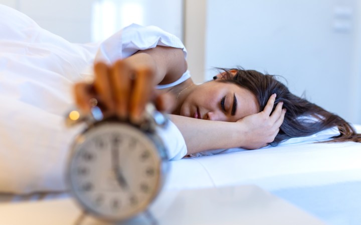 femeie se trezește greu dimineața când sună alarma