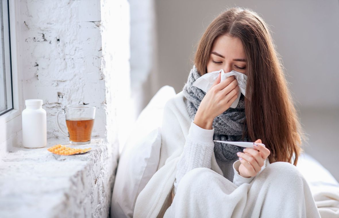 O femeie cu simptome de gripă verifică temperatura