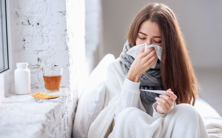 O femeie cu simptome de gripă verifică temperatura
