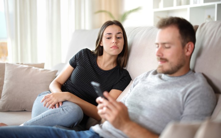 femeie se uită suspicioasă în telefonul partenerului